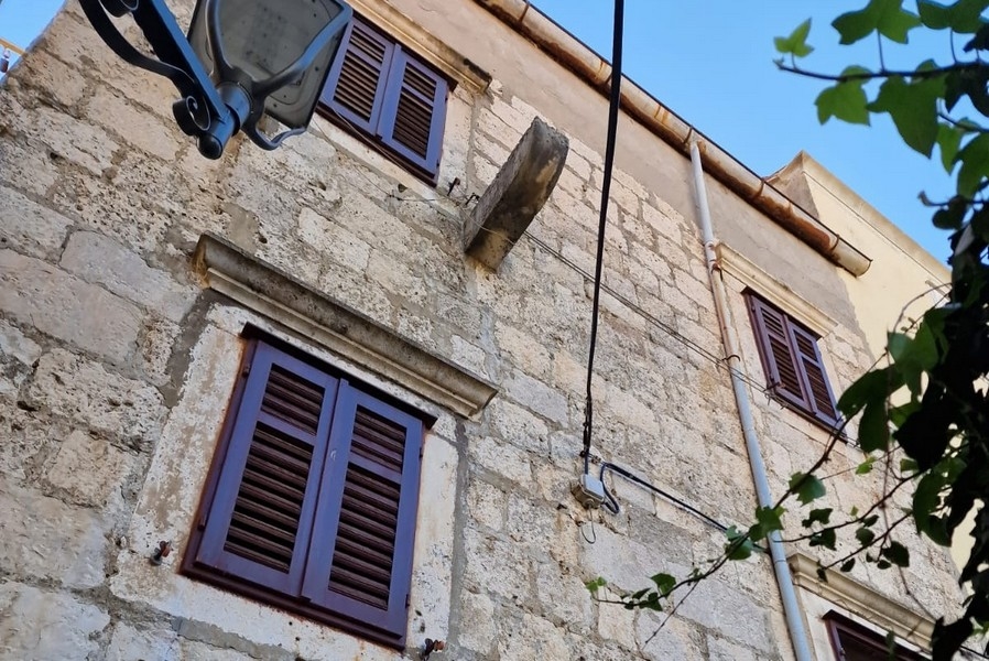 Fasáda kamenného domu s okenicemi a zdmi z přírodního kamene