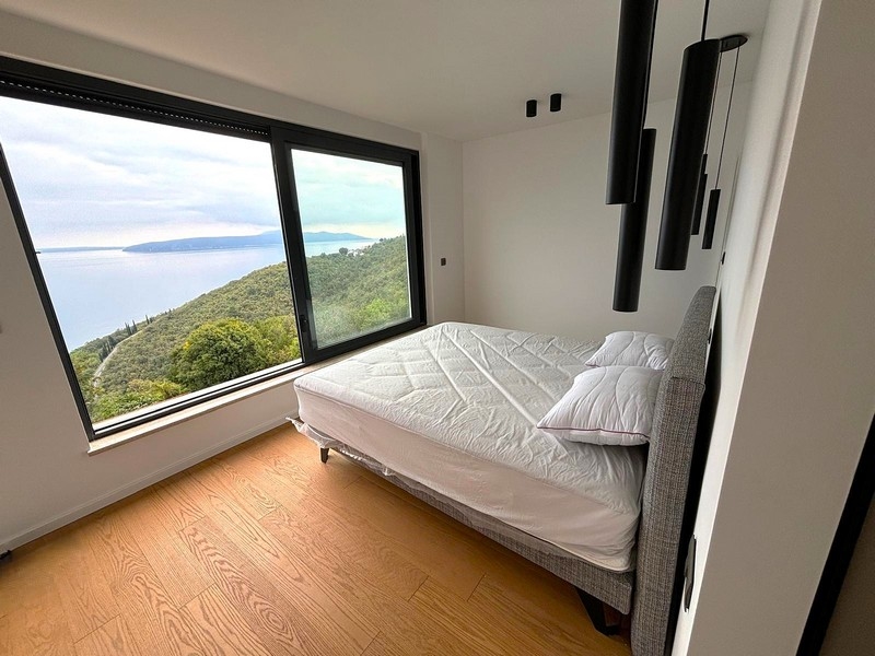 Světlá ložnice s velkým oknem a výhledem na moře