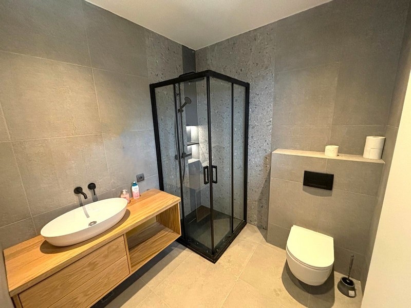 Moderní koupelna s proskleným sprchovým koutem a dřevěným umyvadlem