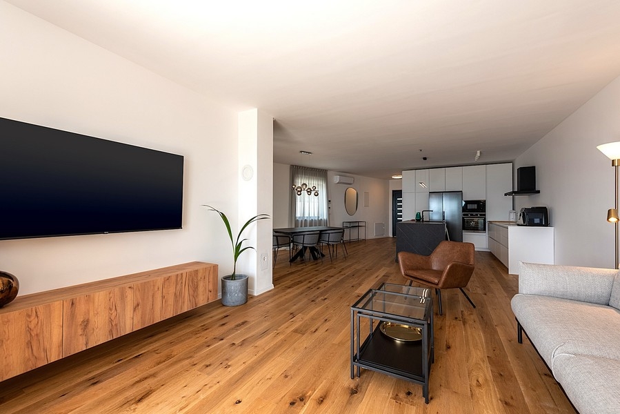 Otevřený obývací prostor s kuchyní, jídelním koutem a světlým nábytkem