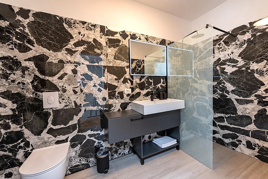 Moderní koupelna s černou mramorovou stěnou a sprchovým koutem