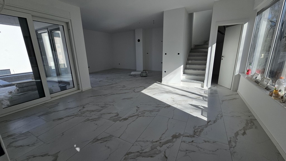 Světlý obývací pokoj s mramorovými podlahami a schodištěm