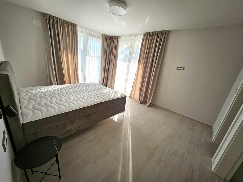 Světlá ložnice s manželskou postelí, závěsy a balkonovými dveřmi