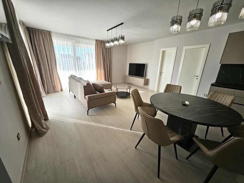 Světlý obývací pokoj se sedací soupravou a TV, velká okna