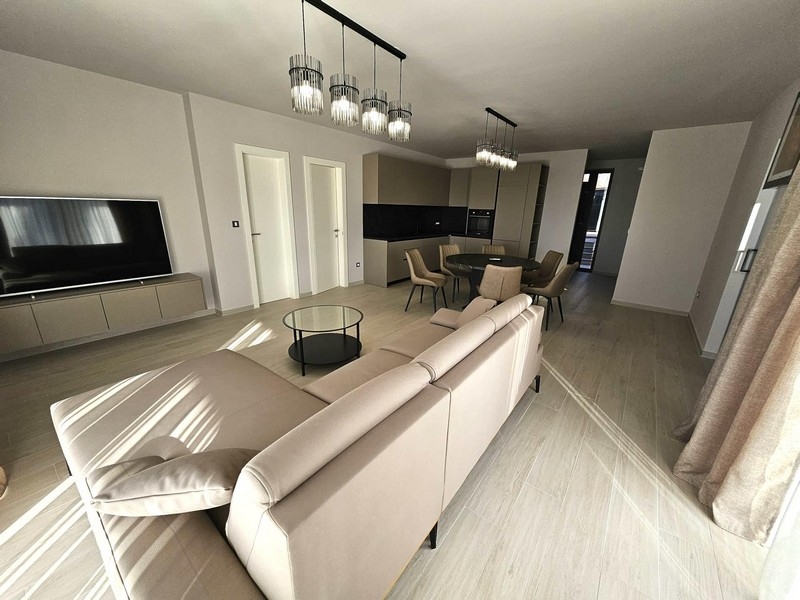 Otevřený obývací prostor s pohovkou, TV a designovými lampami