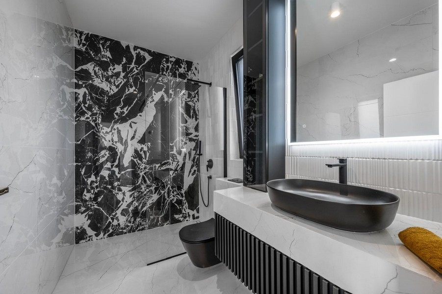 Stylová koupelna s mramorovými obklady a černým nábytkem