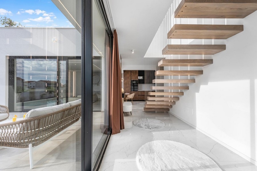 Světlá galerie s plovoucím schodištěm a velkými okny