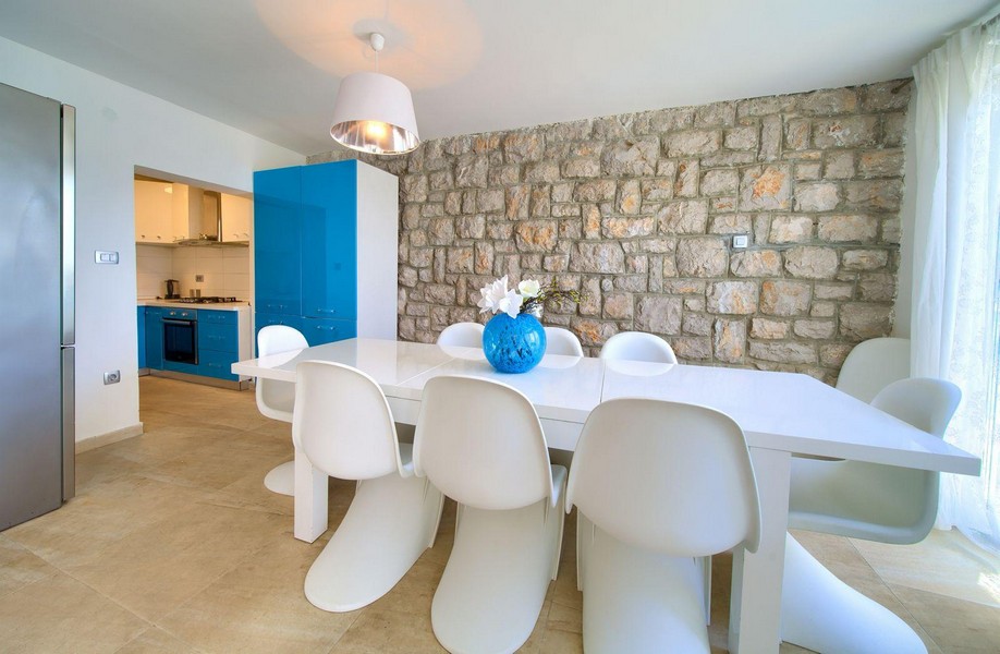 Světlý jídelní kout se stěnou z přírodního kamene a výhledem do kuchyně