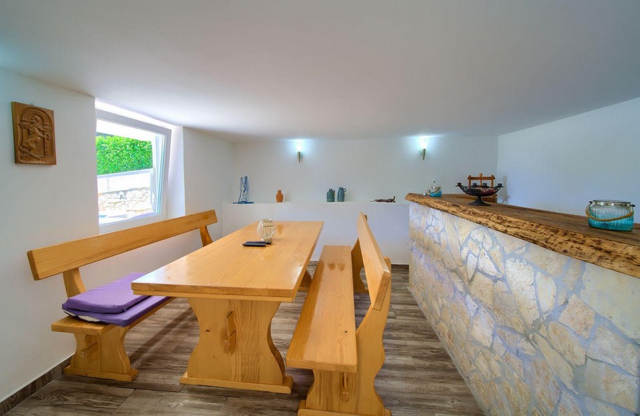 Útulná hobby místnost s dřevěným stolem a kamenným barem