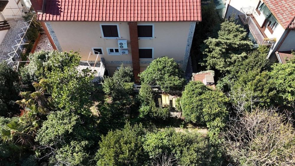 Zadní pohled na dům se zelenou zahradou a posezením