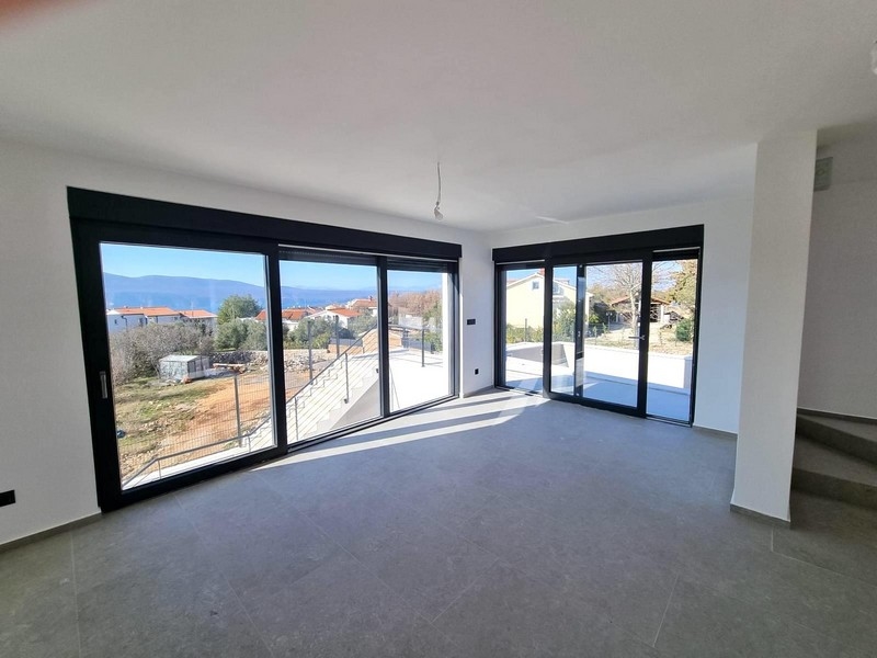 Obývací pokoj s velkými prosklenými čely a výhledem na moře