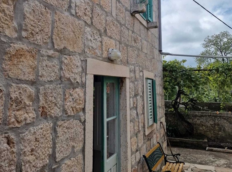 Kamenná fasáda s vchodem a okenicemi