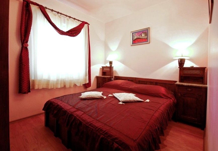 Ložnice s manželskou postelí a červeným ložním prádlem