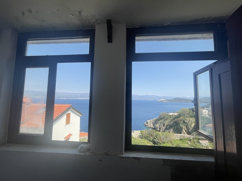 Pohled oknem na moře a pobřeží