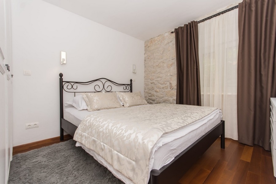 Ložnice s manželskou postelí a kamennou zdí