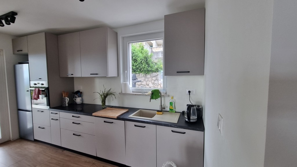 Moderně vybavená kuchyně s oknem a výhledem do zahrady