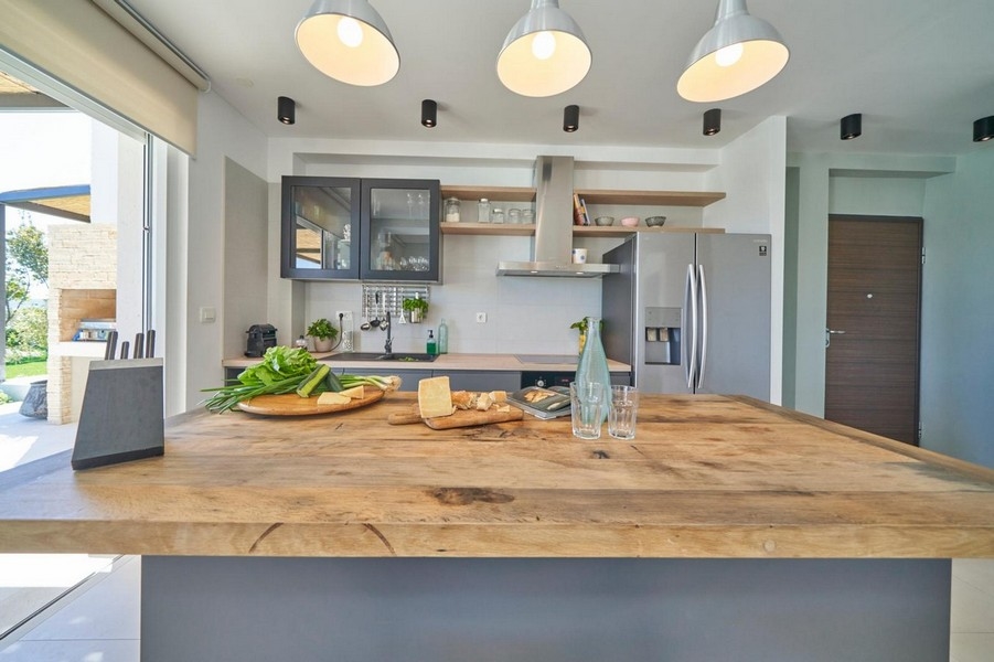 Kuchyňský ostrůvek s dřevěnou pracovní deskou a lampami