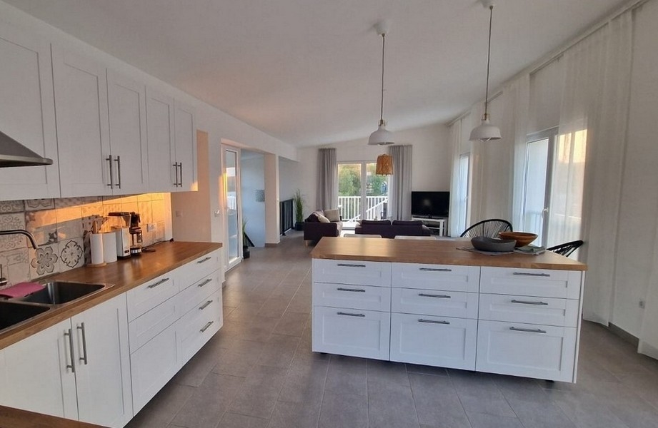 Světlá kuchyně s ostrůvkem na vaření a obývací částí