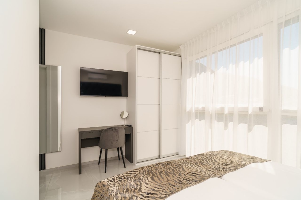 Světlá ložnice s psacím stolem a TV