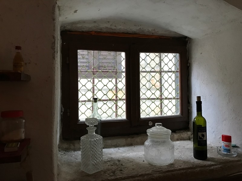 Okno s mřížemi a skleněnými lahvemi