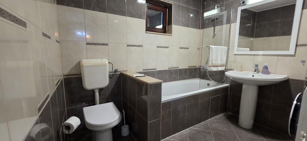 Koupelna s vanou a světlými obklady