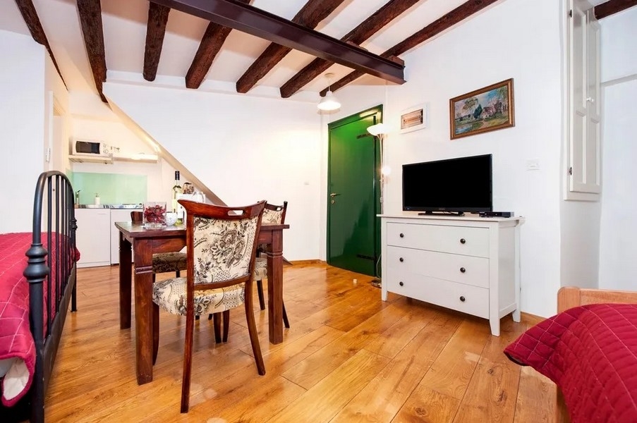 Studio s dřevěnými podlahami, TV a otevřenou kuchyní