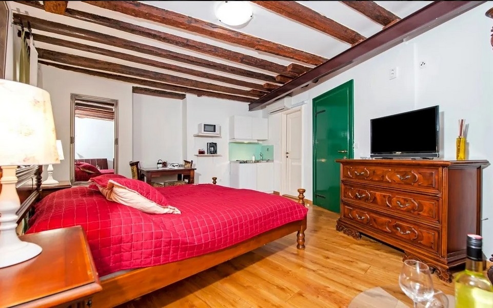 Útulné studio se zeleným vchodem a TV