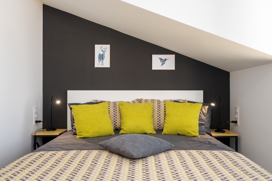 Podkrovní ložnice s manželskou postelí a žlutými polštáři