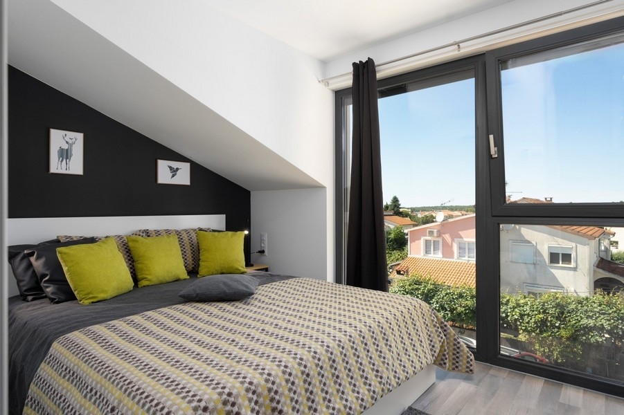 Podkrovní ložnice s velkým oknem a výhledem