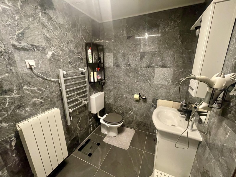 Moderní koupelna se sprchovým koutem, toaletou a šedými obklady