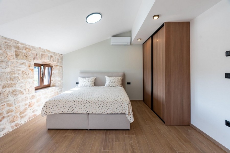 Světlá ložnice se zdí z přírodního kamene