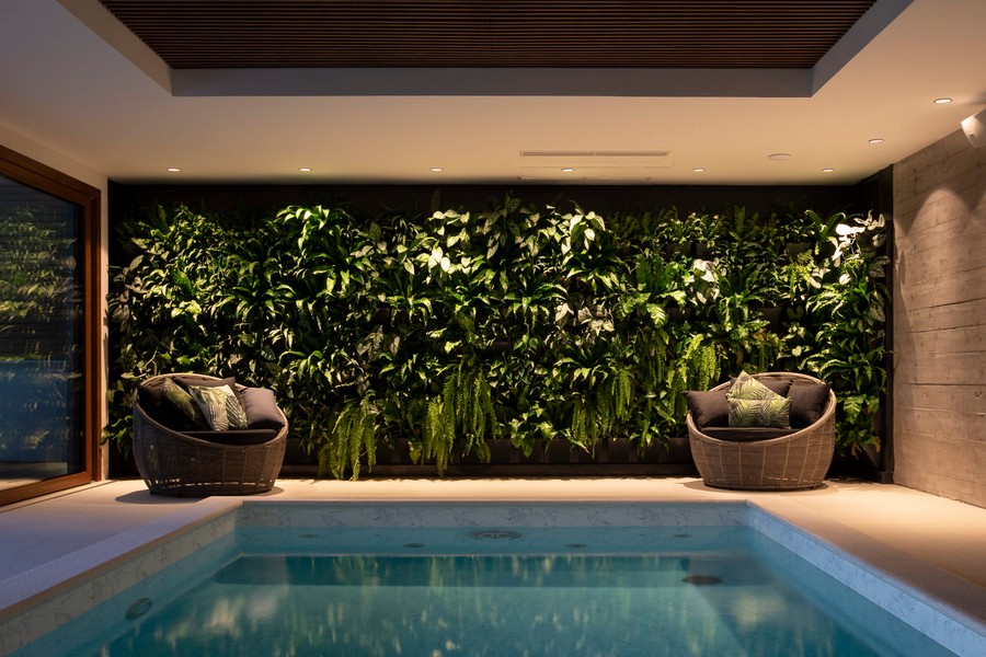 Krytý bazén se stěnou ze zelených rostlin a posezením