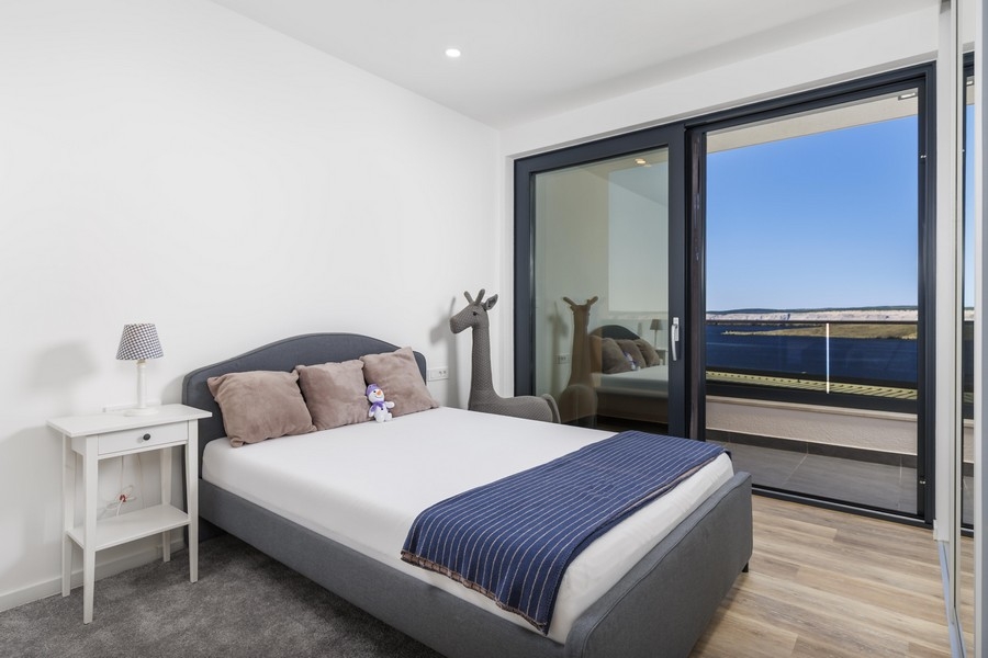 Světlá ložnice se vstupem na balkon a výhledem na moře
