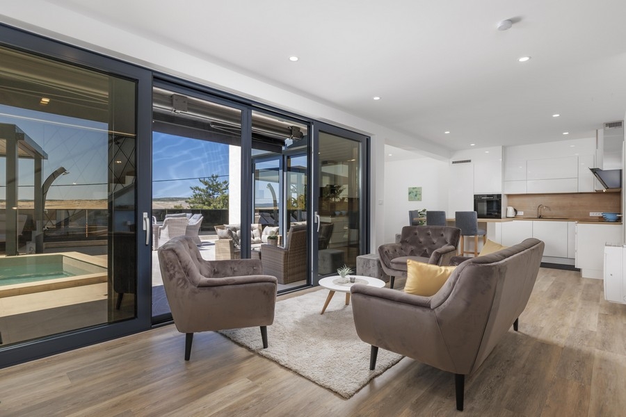 Moderní obývací pokoj s výhledem na terasu a bazén