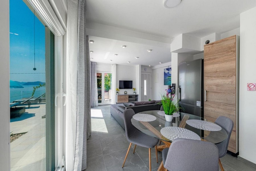 Jídelna se skleněným stolem a přístupem na terasu s výhledem na moře