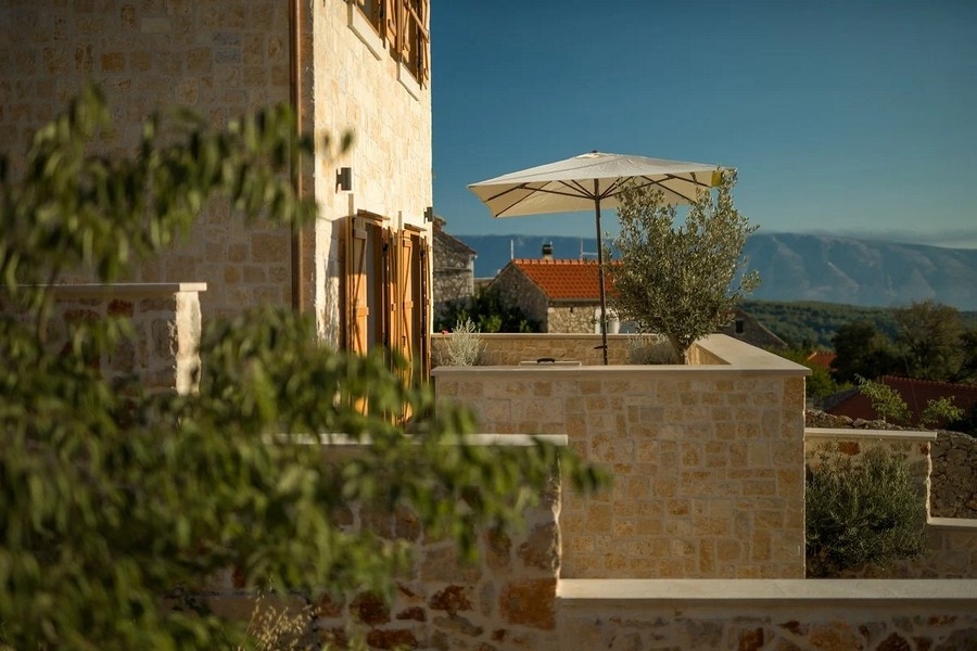 Kamenný dům s terasou a slunečníkem, výhled na hory