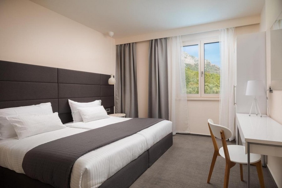 Světlá ložnice s manželskou postelí a výhledem na hory