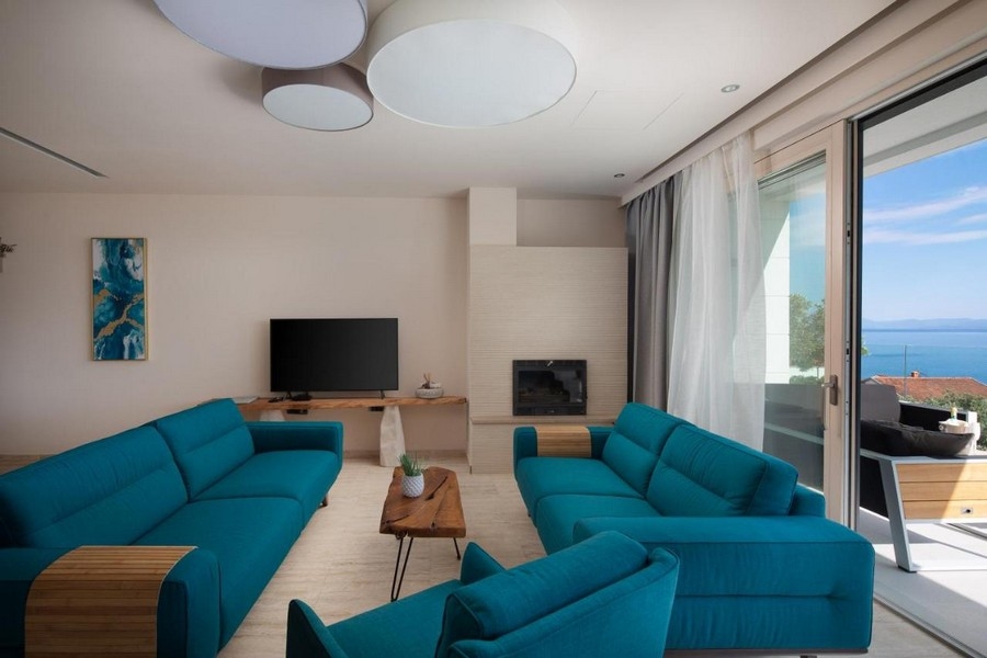 Moderní obývací pokoj s modrými pohovkami a výhledem na moře