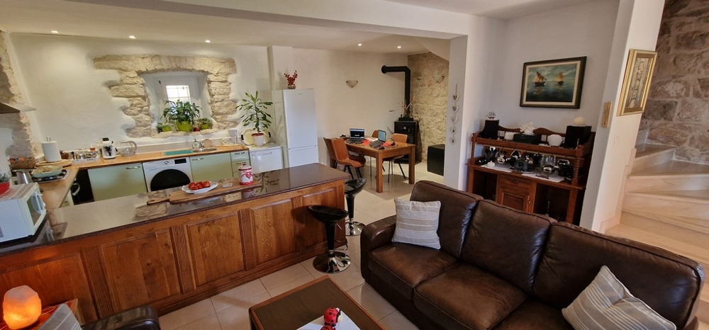 Obývací pokoj s kuchyní, jídelním koutem a zdí z přírodního kamene