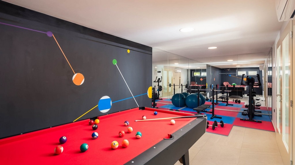Místnost pro volný čas a fitness s kulečníkem a cvičebním zařízením
