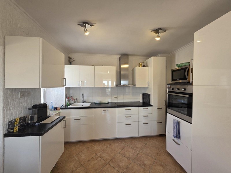 Moderní vybavená kuchyně s bílými vysoce lesklými čely