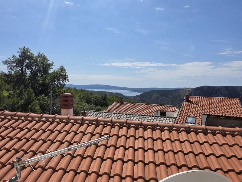 Výhled ze střechy přes taškovou střechu na moře