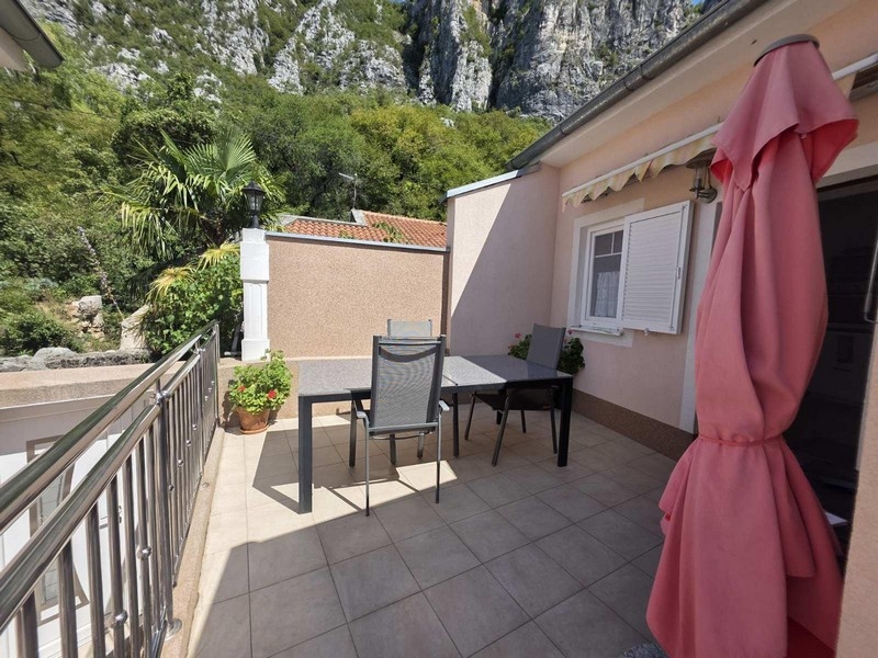 Terasa se stolem, židlemi a výhledem na skály