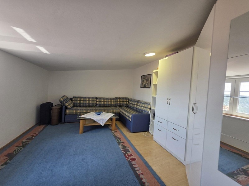 Obývací pokoj s rohovou pohovkou, kobercem a skříní