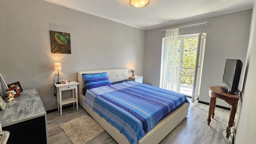 Světlá ložnice s manželskou postelí a vstupem na balkon