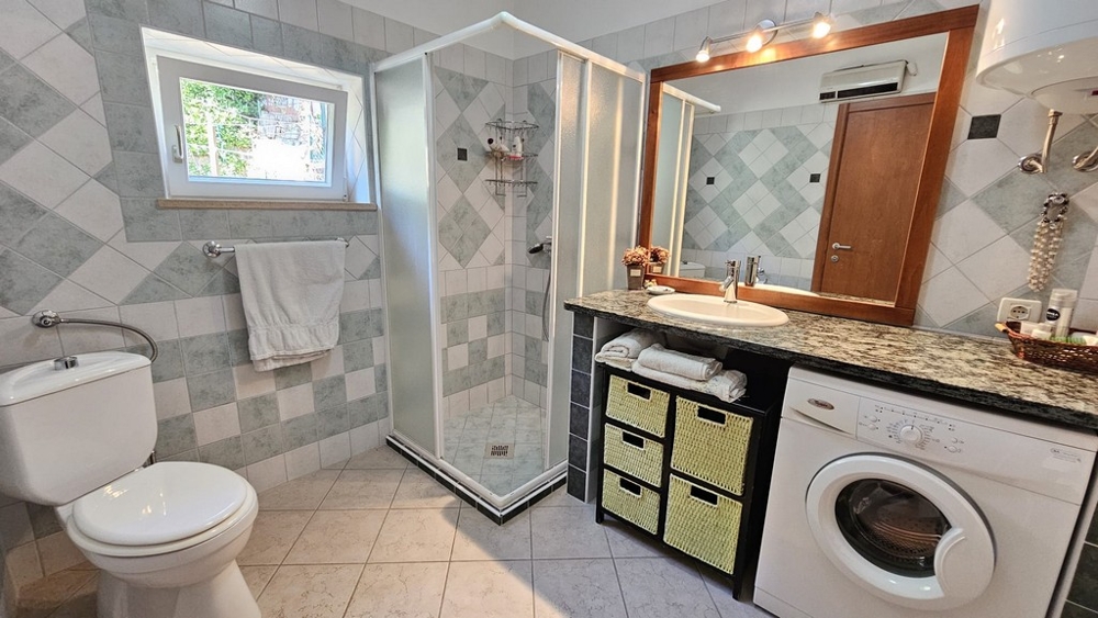 Koupelna se sprchovým koutem, umyvadlem a pračkou