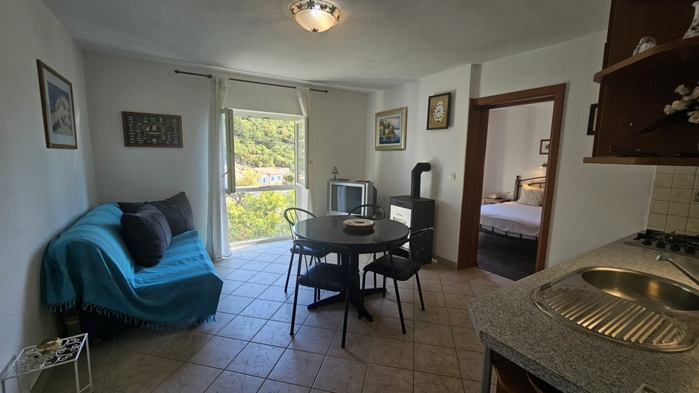 Obývací pokoj s pohovkou, jídelním stolem a kuchyňským koutem