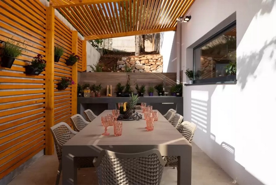 Krytá letní kuchyně s jídelním stolem a pergolou