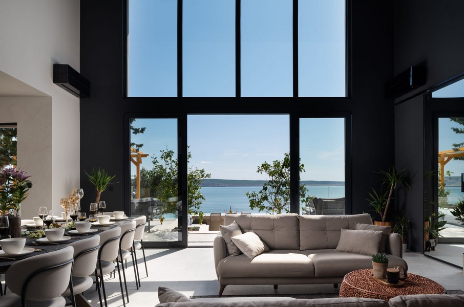 Obývací pokoj s velkými panoramatickými okny a výhledem na moře
