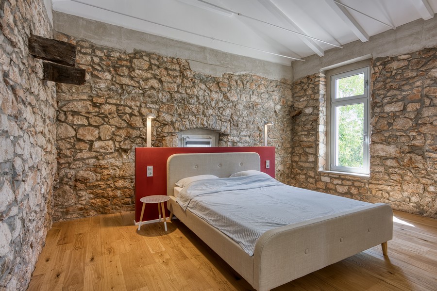 Ložnice se stěnami z přírodního kamene a dřevěnou podlahou